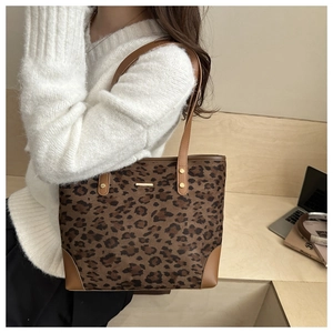 Close-up of leopard print tote bag with brown leather handles and reinforced base corners