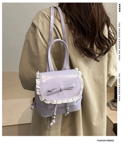 Close-up of lilac mini backpack featuring lace trim, bow detail, and drawstring hardware
