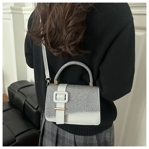 Detailed back view of a white leather handbag with silver glitter flap and square buckle