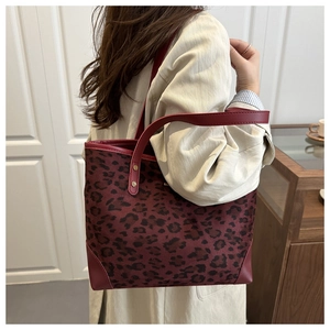 Detailed view of the red leopard print tote bag with gold rivets and leather trim