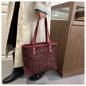 Close-up of burgundy leopard print tote bag featuring gold rivets and leather corner pads