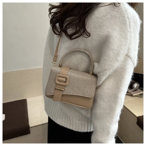 Detail view of beige small crossbody bag with rhinestone handle on white knit sweater