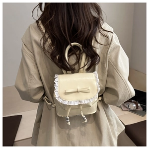 Close-up of cream PU leather backpack with lace trim and bow knot detail on model