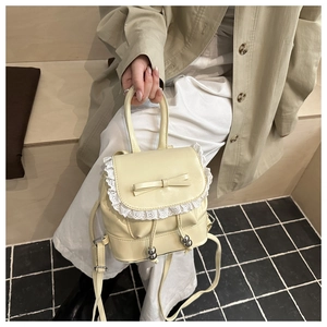 Detail of cream mini backpack featuring a ribbon bow and delicate white lace trim