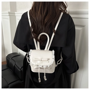Detailed macro view of white mini backpack with lace edges and decorative bow