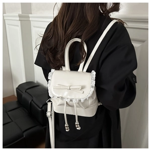 Detail of white mini backpack featuring lace trim, bow knot and drawstring closure
