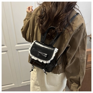 Close-up of mini black backpack featuring white lace trim and delicate bow detail