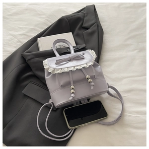 Detail of light purple PU leather handbag featuring white lace ruffles and bow decoration