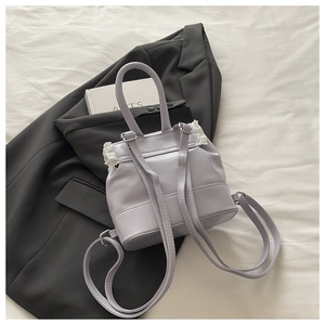 Detail of light purple PU leather mini backpack with white lace trim and silver hardware