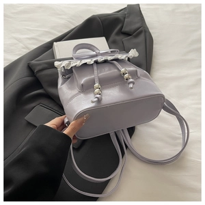 Detail of light purple mini backpack with lace edges, bow and drawstring closure
