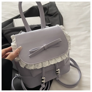 Detail of lavender PU mini bag featuring white lace trim and bow with metallic drawstring