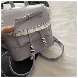 Close-up of lavender PU handbag with delicate white lace trim and leather bow detail