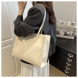 Detailed side view of off-white lychee grain leather tote bag on shoulder