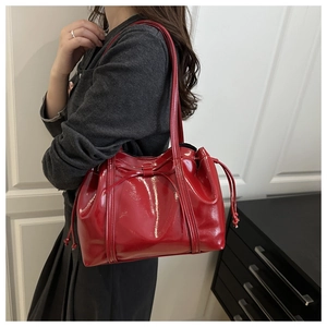 Close-up of a red patent leather shoulder bag with bow detail and drawstring sides