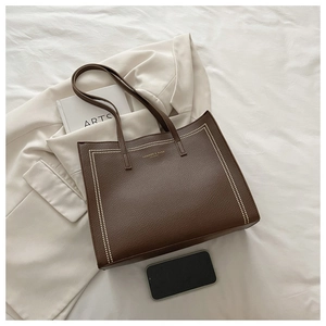 Detail of a brown lychee pattern tote bag with golden lettering and soft leather texture