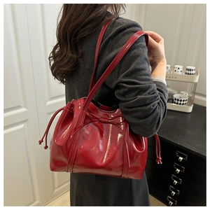 Detail of red patent leather bucket bag with bow decoration and drawstring closure