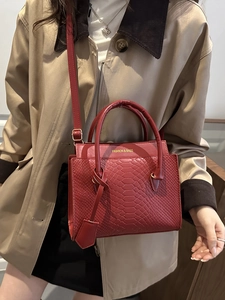 Elegant deep red embossed pattern handbag with top handles and slender shoulder strap