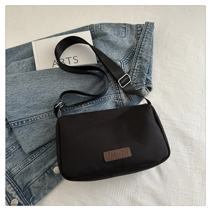 Détail du sac bandoulière noir avec patch en cuir marron FASHION sur fond blanc