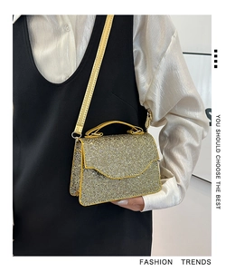 Detail of golden rhinestone handbag featuring a sleek metallic strap and shimmering finish
