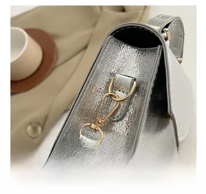 Detailed close-up of premium gold metal hooks and hardware on a silver evening bag