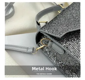 Detail of silver rhinestone handbag showing golden metal D-ring and leather strap hook