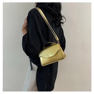Side view of a gold textured evening clutch with luxury chain strap on female model