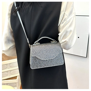 Close-up of a silver rhinestone evening handbag with chain strap shown on a model