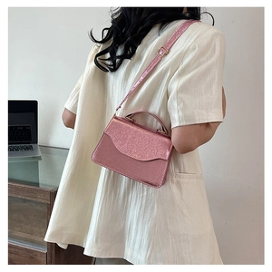 Detailed view of pink metallic crossbody bag with sequin texture and round handle