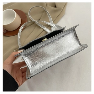 Detail of silver metallic evening bag showing textured material and magnetic closure