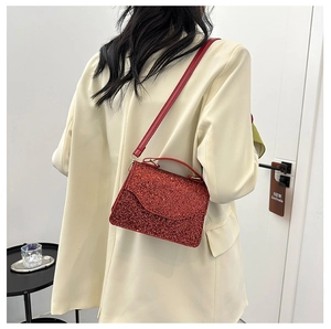 Macro shot of red rhinestone handbag with shimmering finish on beige suit blazer