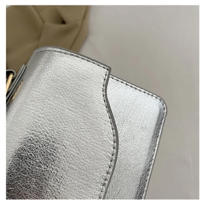Close-up of silver textured leather evening bag with precise stitching and refined edges
