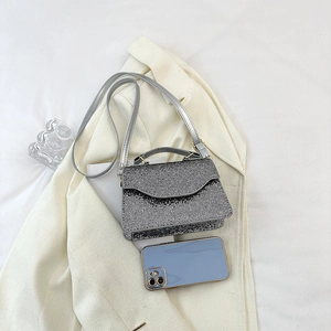 Mini silver rhinestone evening bag with chain strap shown next to a large smartphone