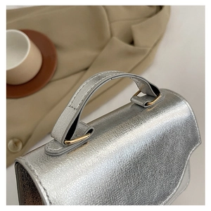 Detailed macro view of silver crinkle leather texture and gold metal chain links on handbag