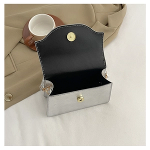 Top view of open silver evening clutch with gold magnetic clasp and black interior