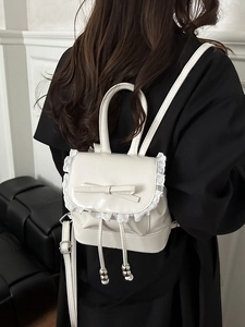 Cream pleated mini backpack with lace trim and bow detail on model back view