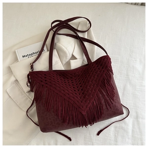 Detail view of burgundy tote with bohemian knit tassels and subtle leopard print texture