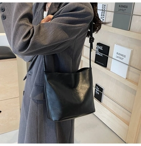 Détail du sac à bandoulière en cuir PU noir avec lettrage embossé et style moderne