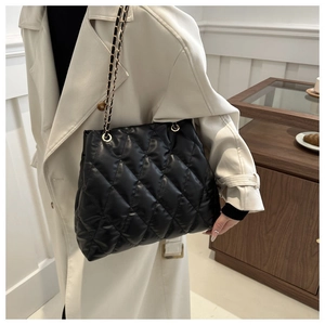 Close-up of black quilted texture and golden chain strap on large capacity bucket tote