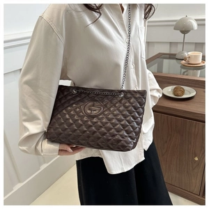 Close-up of quilted rhombus pattern and chain strap on a large brown tote bag