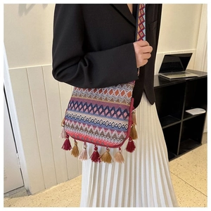 Close-up of bohemian bucket bag with geometric patterns, colorful fringe, and wide strap