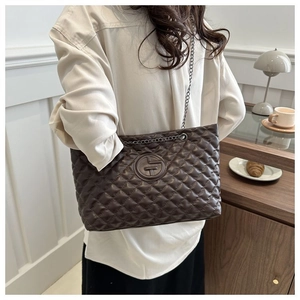 Detail of dark brown quilted crossbody bag with metal chain strap in cafe setting