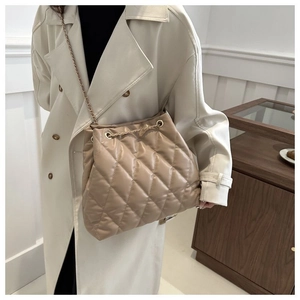 Detail of quilted apricot bucket bag with chain strap and soft leather texture