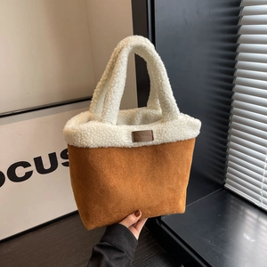 Brown suede tote bag with white faux shearling trim and top handles in a hand-held view