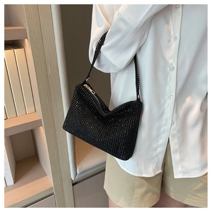 Detalle de bolso hobo con pedrería negra y cierre de cremallera en una modelo