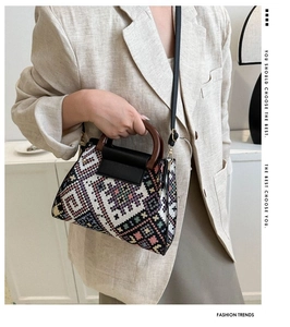 Detailed view of the ethnic woven handbag featuring a round wooden handle and leather strap