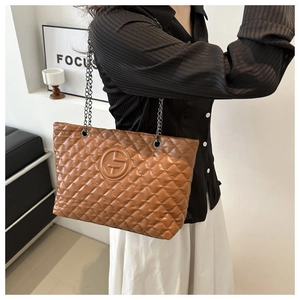 Close-up of brown quilted leather tote bag with chain strap and embossed logo detail