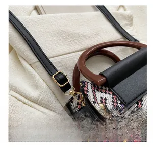 Detail of adjustable black leather strap with gold metal buckle on woven handbag