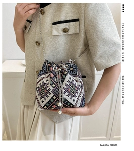 Detail of colorful ethnic woven bucket bag with pearl drawstring and silver chain strap