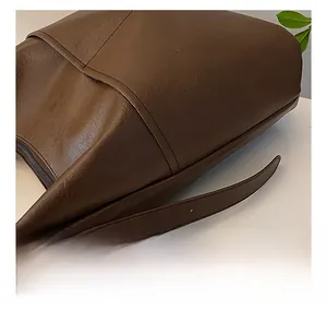 Close-up of brown pebbled leather tote bag showing detailed stitching and adjustable strap