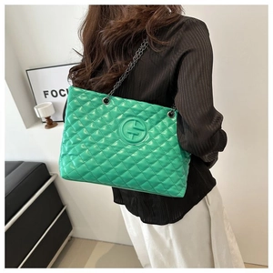 Detail of green quilted tote bag with silver chain strap and metallic logo plaque